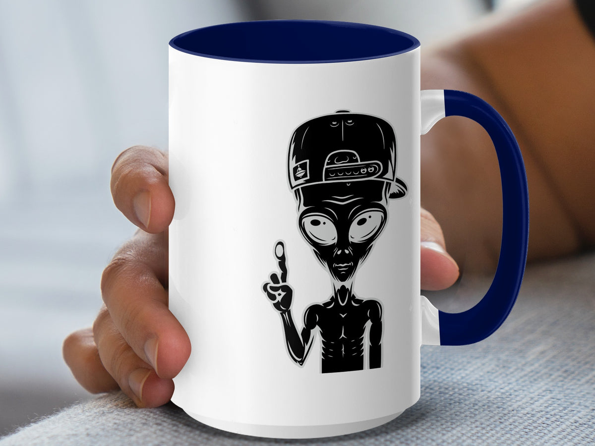 White mug with navy blue rim and handle, featuring a black alien graphic.