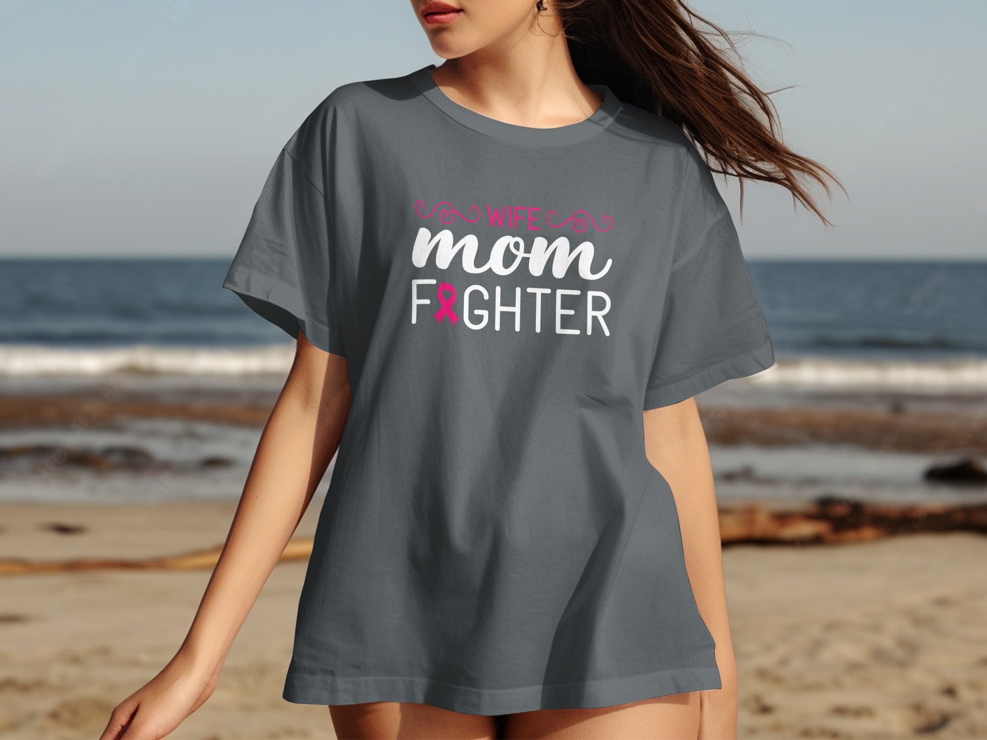 Gray t-shirt with "Wife Mom Fighter" text and pink ribbon on beach background.
