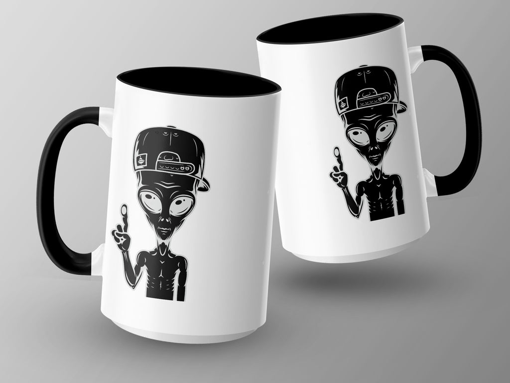 Two white mugs with black handles, each featuring a black alien graphic wearing a baseball cap.