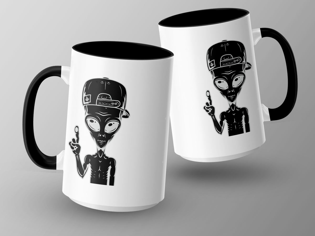 Two white mugs with black handles, each featuring a black alien graphic wearing a baseball cap.