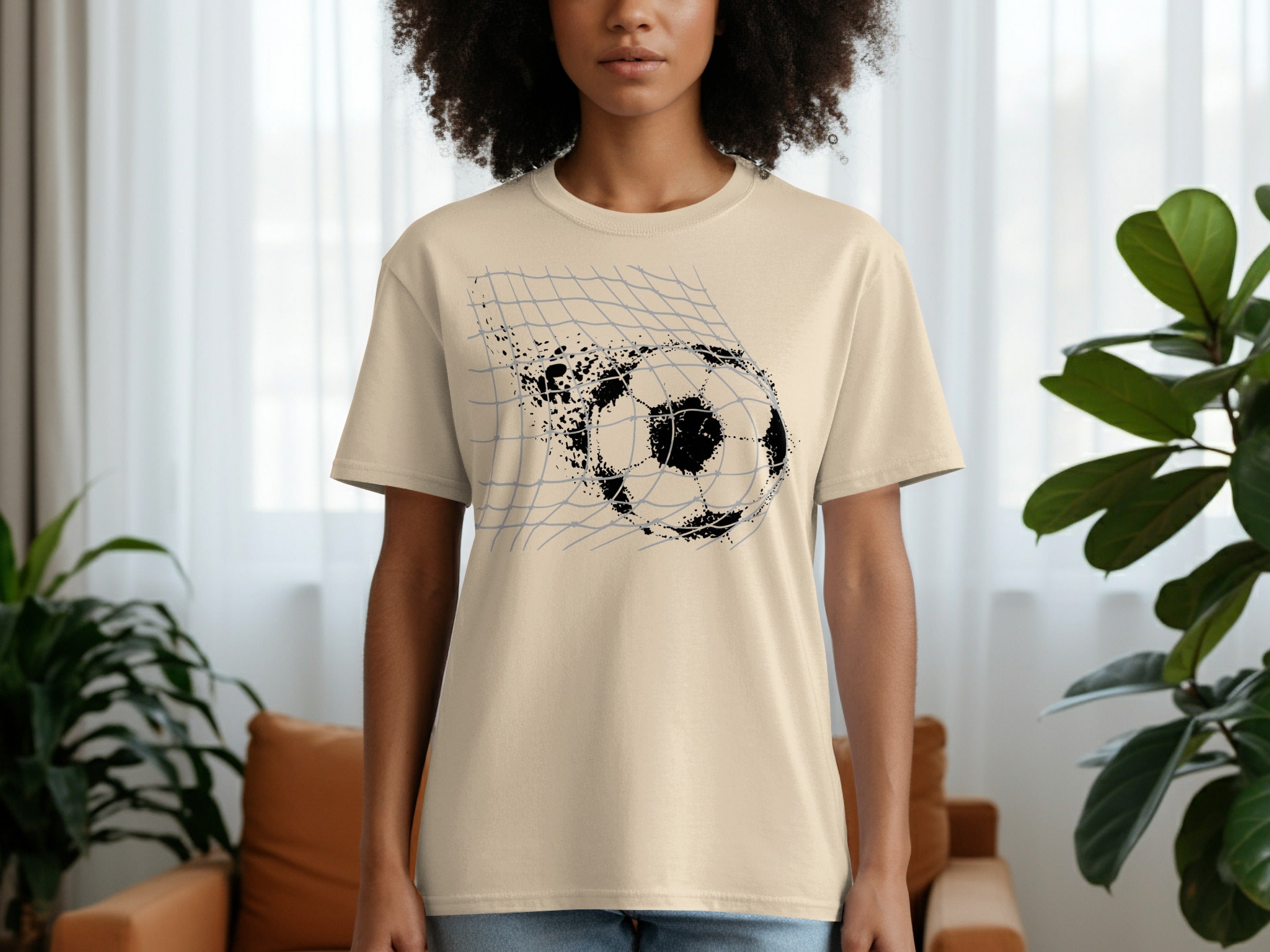 Cream t-shirt with black graphic of a soccer ball breaking through a net.