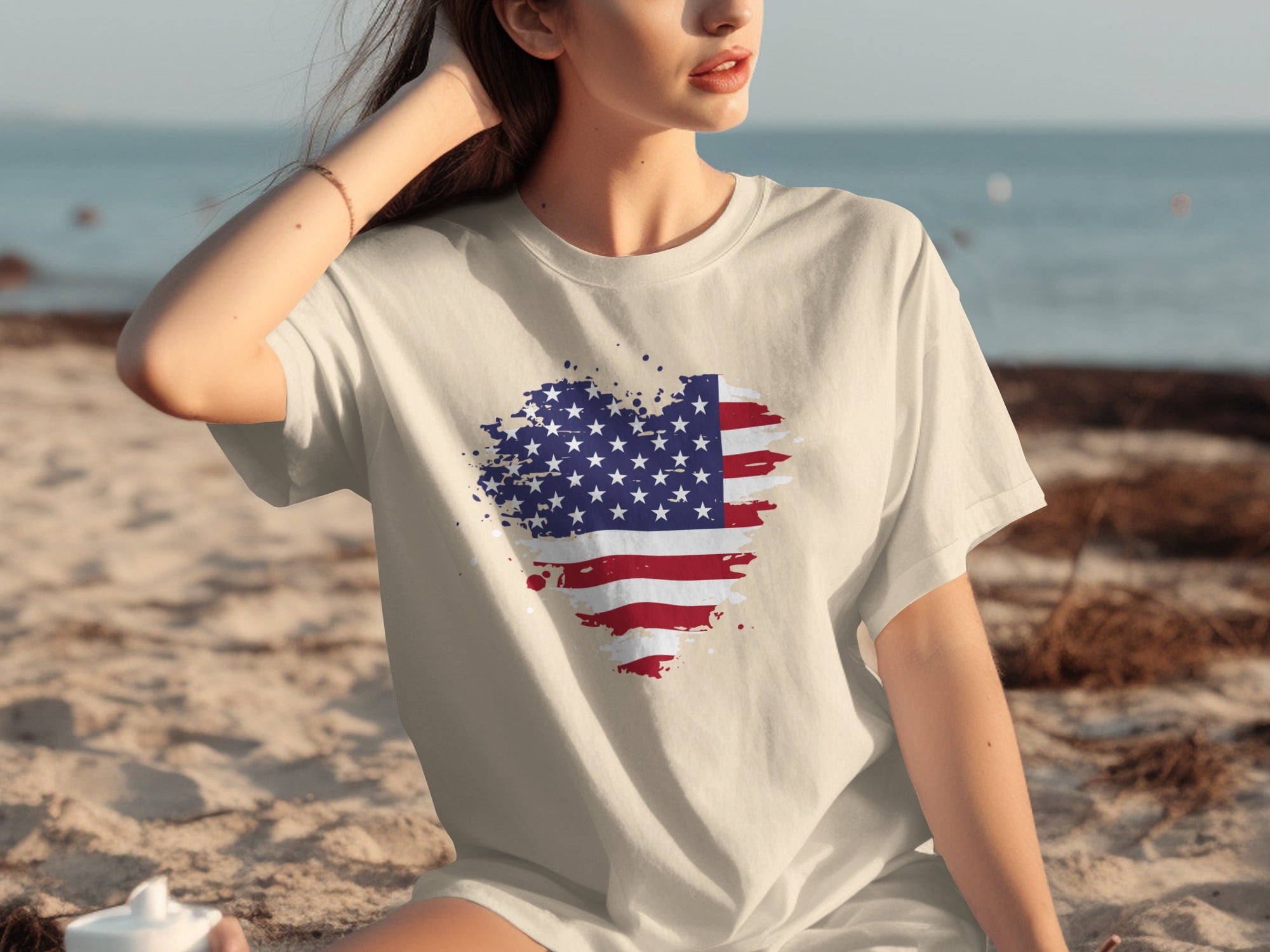 Cream t-shirt with distressed American flag heart graphic on a beach