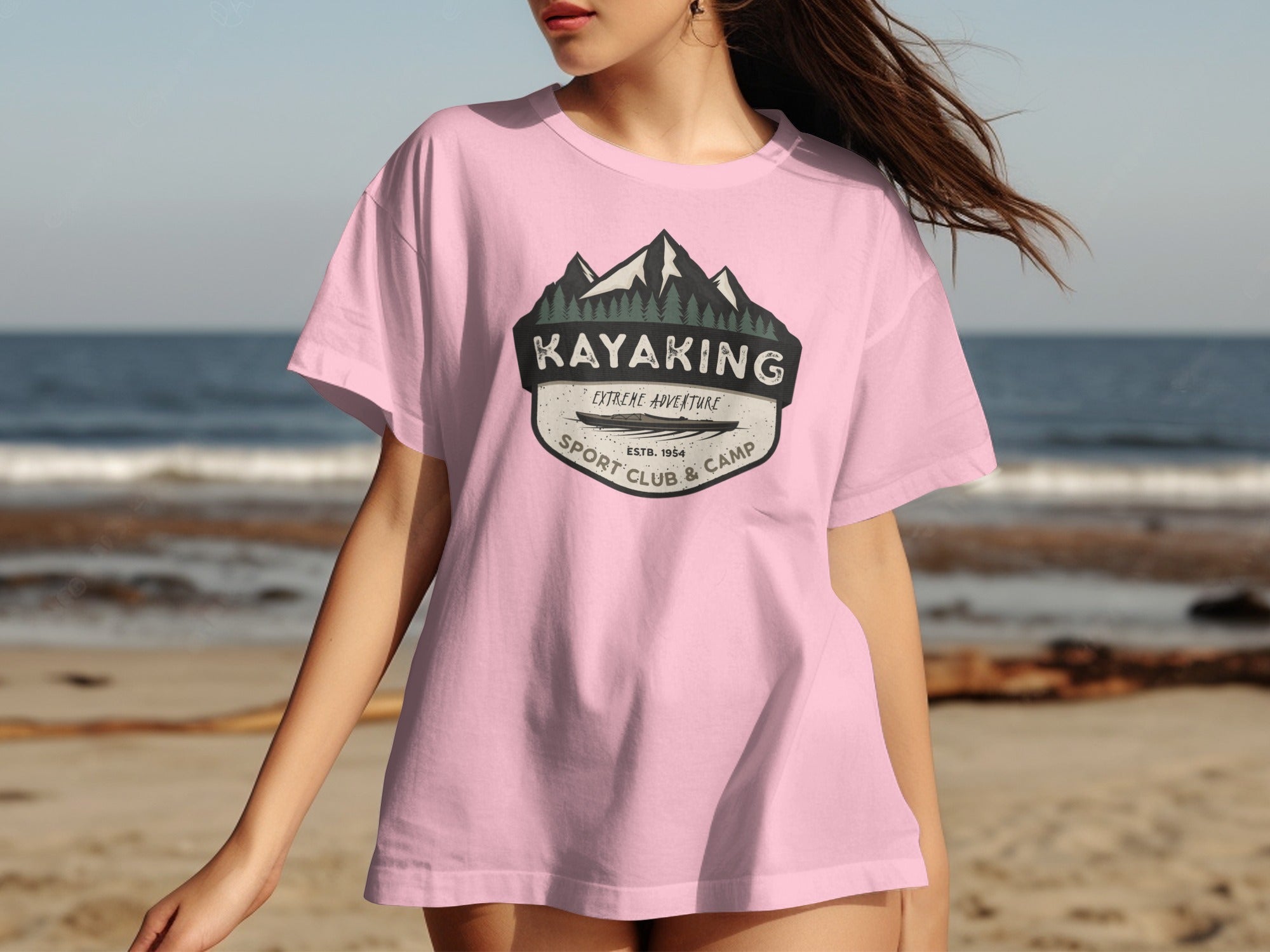 Pink t-shirt with a graphic featuring mountains, trees, kayak, and text.