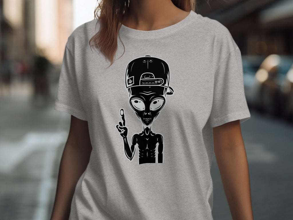 Alien wearing a backwards baseball cap and holding up two fingers on a grey t-shirt.