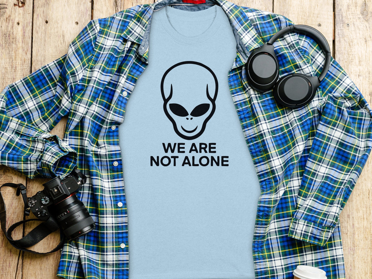 Light blue t-shirt with alien graphic and text "WE ARE NOT ALONE".