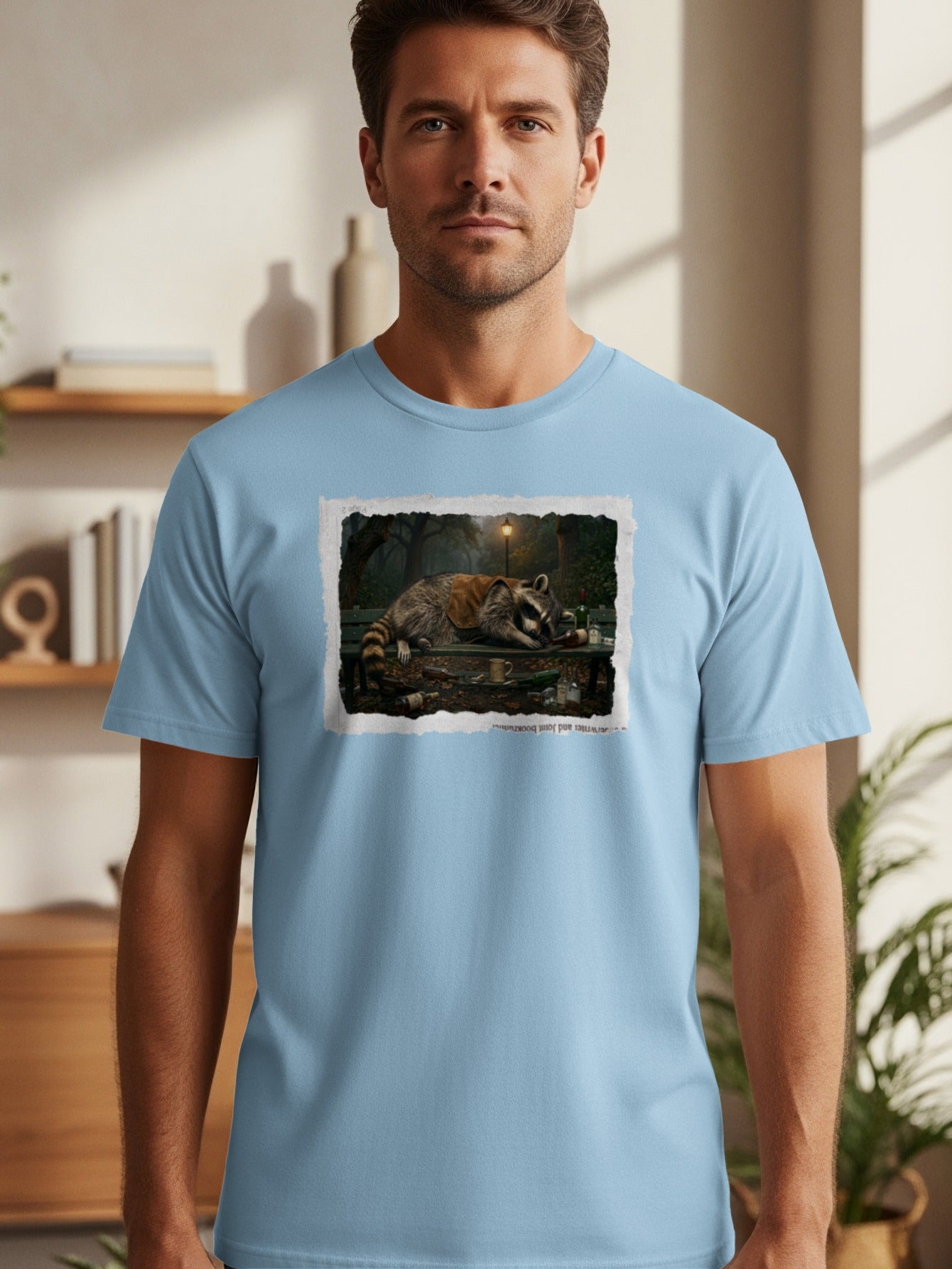 T-shirt with print: raccoon passed out on bench with bottles and light pole.