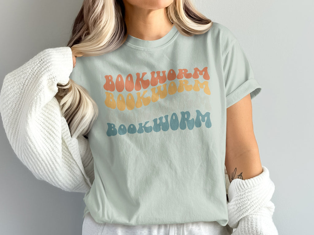 Pale green t-shirt with "BOOKWORM" in three horizontally stacked retro-style fonts and colors.