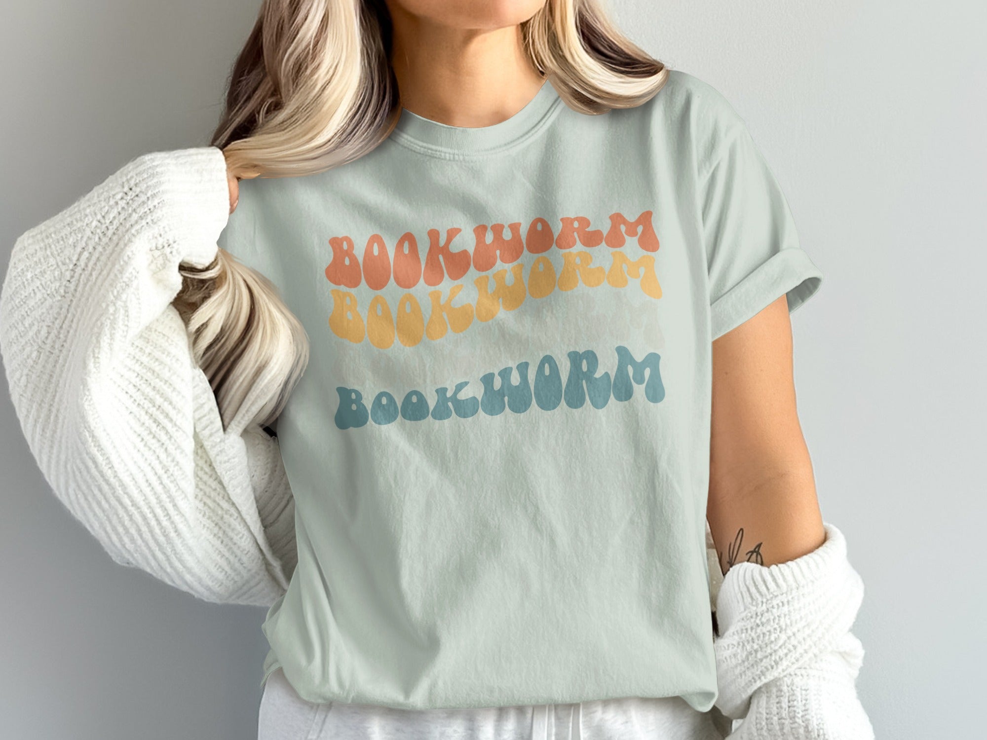 Pale green t-shirt with "BOOKWORM" in three horizontally stacked retro-style fonts and colors.
