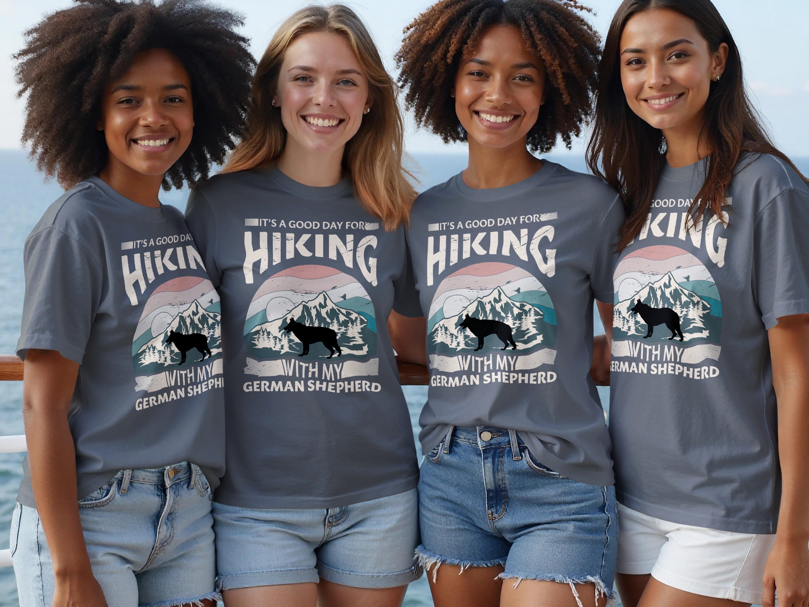 Four women wear grey t-shirts with a hiking-themed German Shepherd graphic and text.