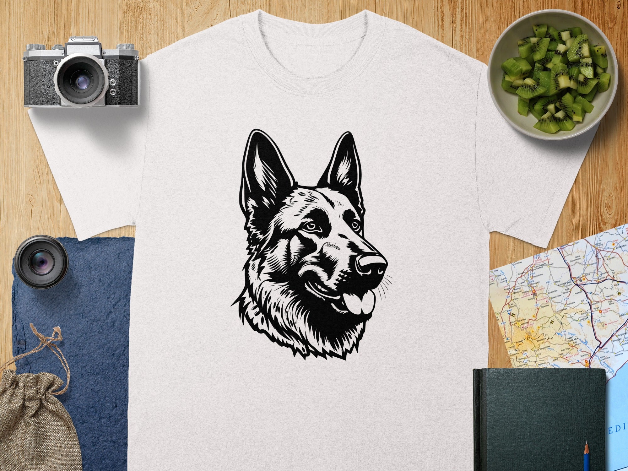 White t-shirt with black German Shepherd illustration and surrounding props.