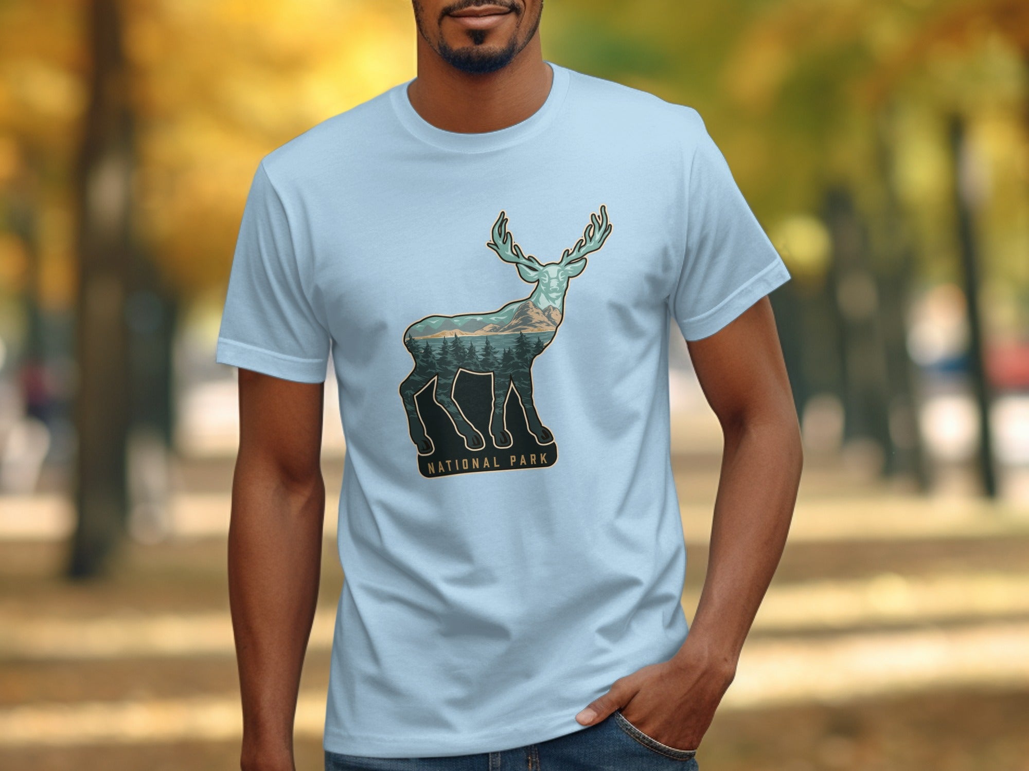 Blue t-shirt with deer silhouette filled with forest, mountains, and lake.