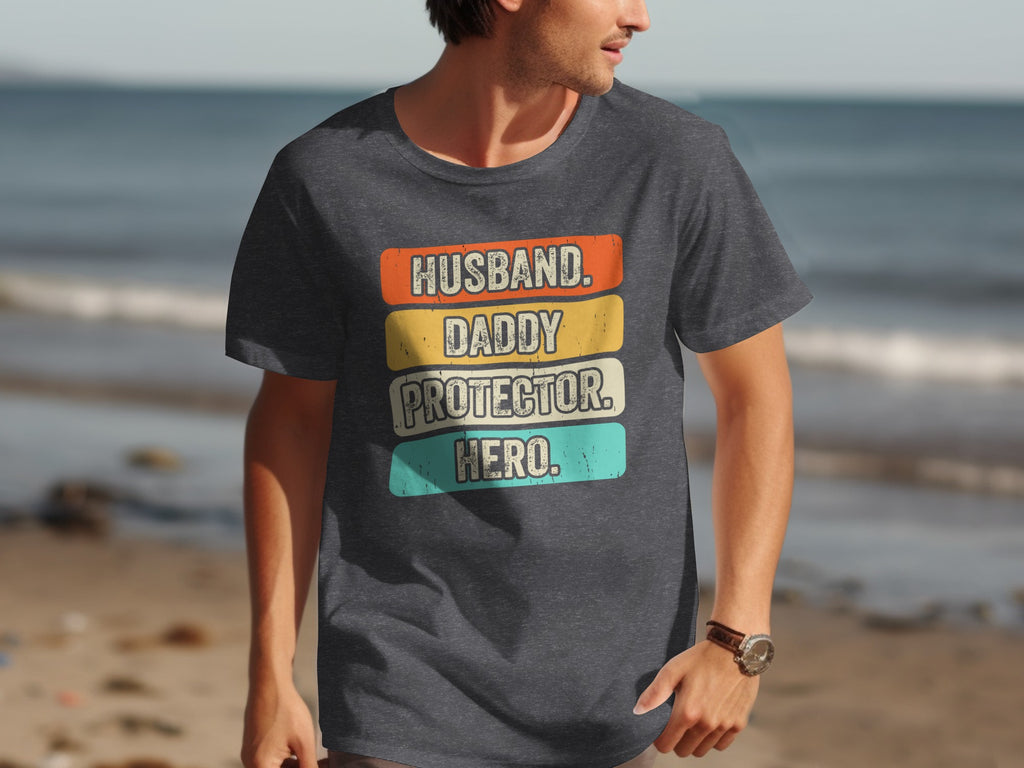 Dark gray t-shirt with text "Husband. Daddy. Protector. Hero." in distressed vintage style.