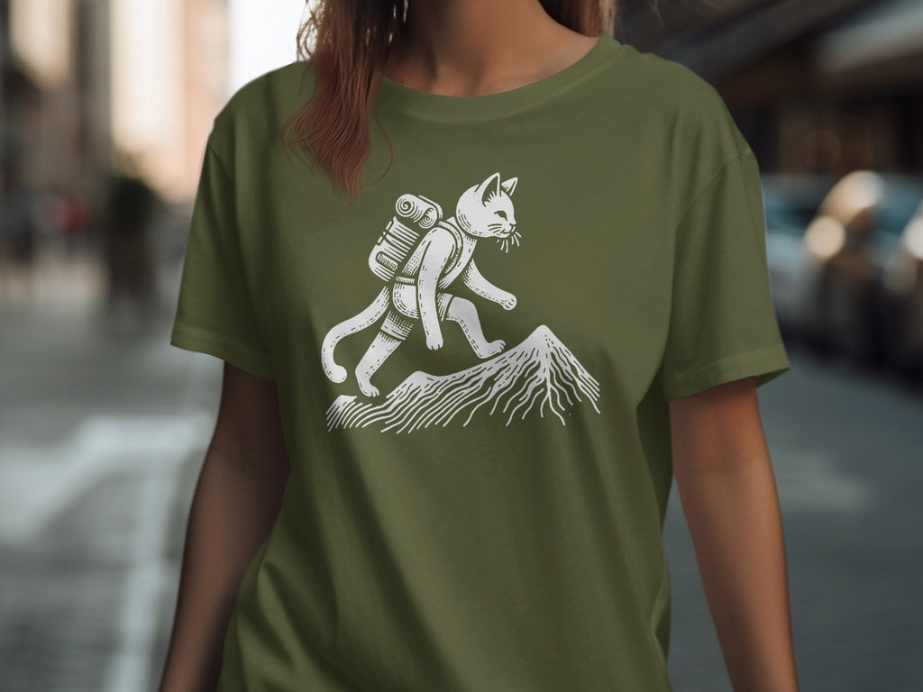 Cat with backpack hiking up a mountain on a green t-shirt.