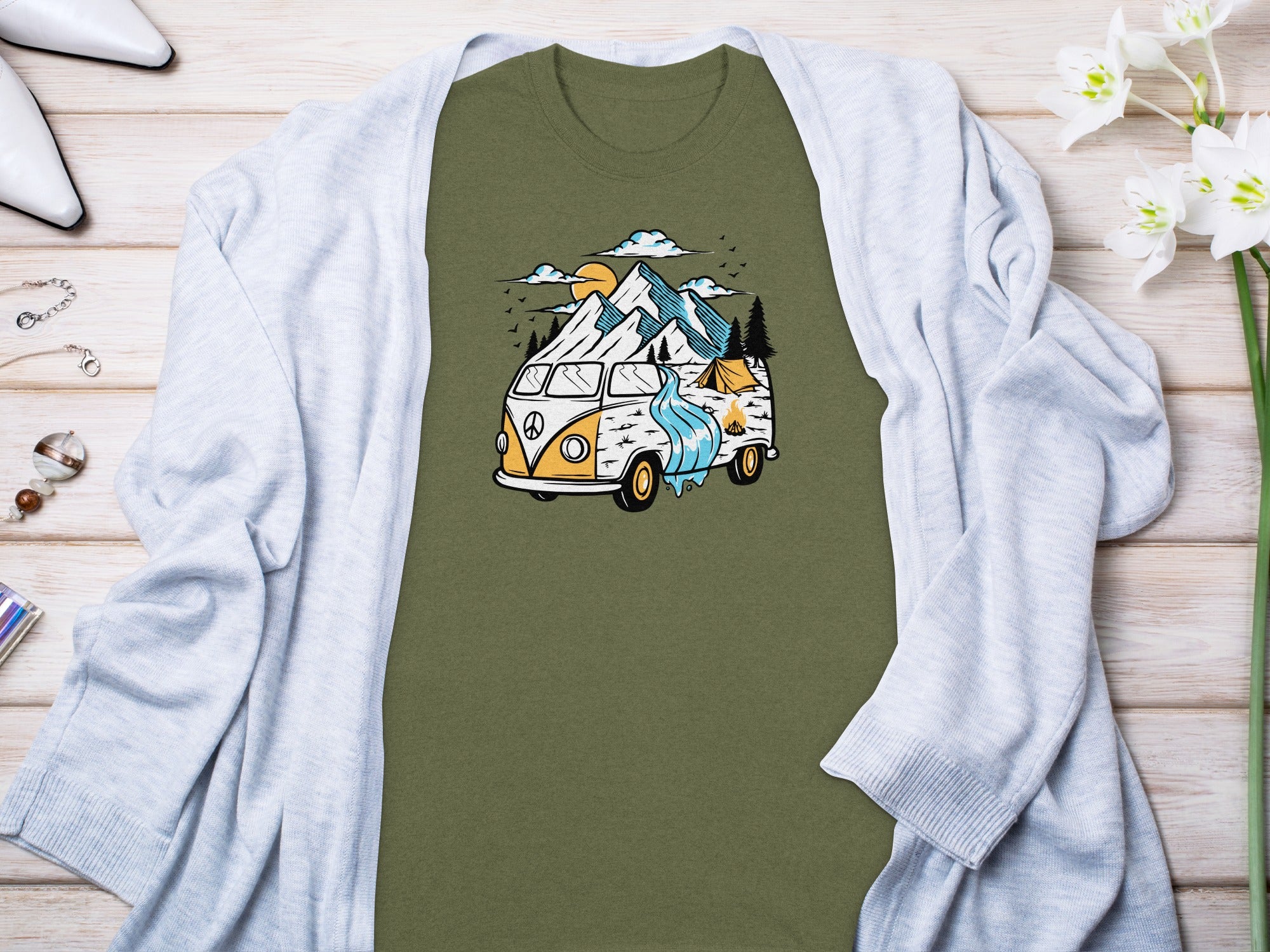 Olive green t-shirt with graphic of camper van, mountains, tent, and campfire.