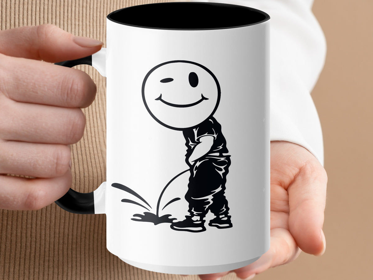White mug with black rim and handle featuring a black graphic of a winking smiley face over a person urinating.