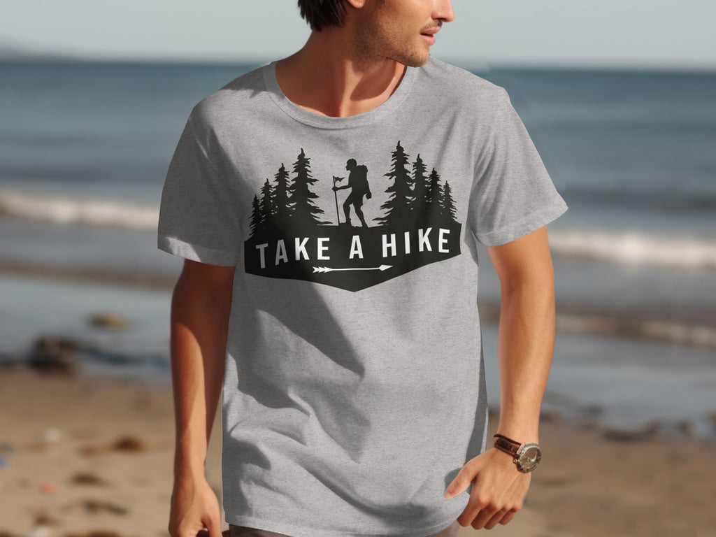 Grey t-shirt with black graphic of a hiker, trees, and "TAKE A HIKE" text.
