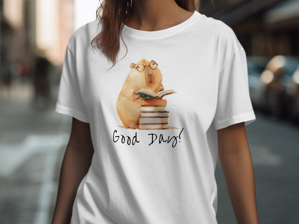 White t-shirt with illustration of a capybara reading a book on a stack of books.