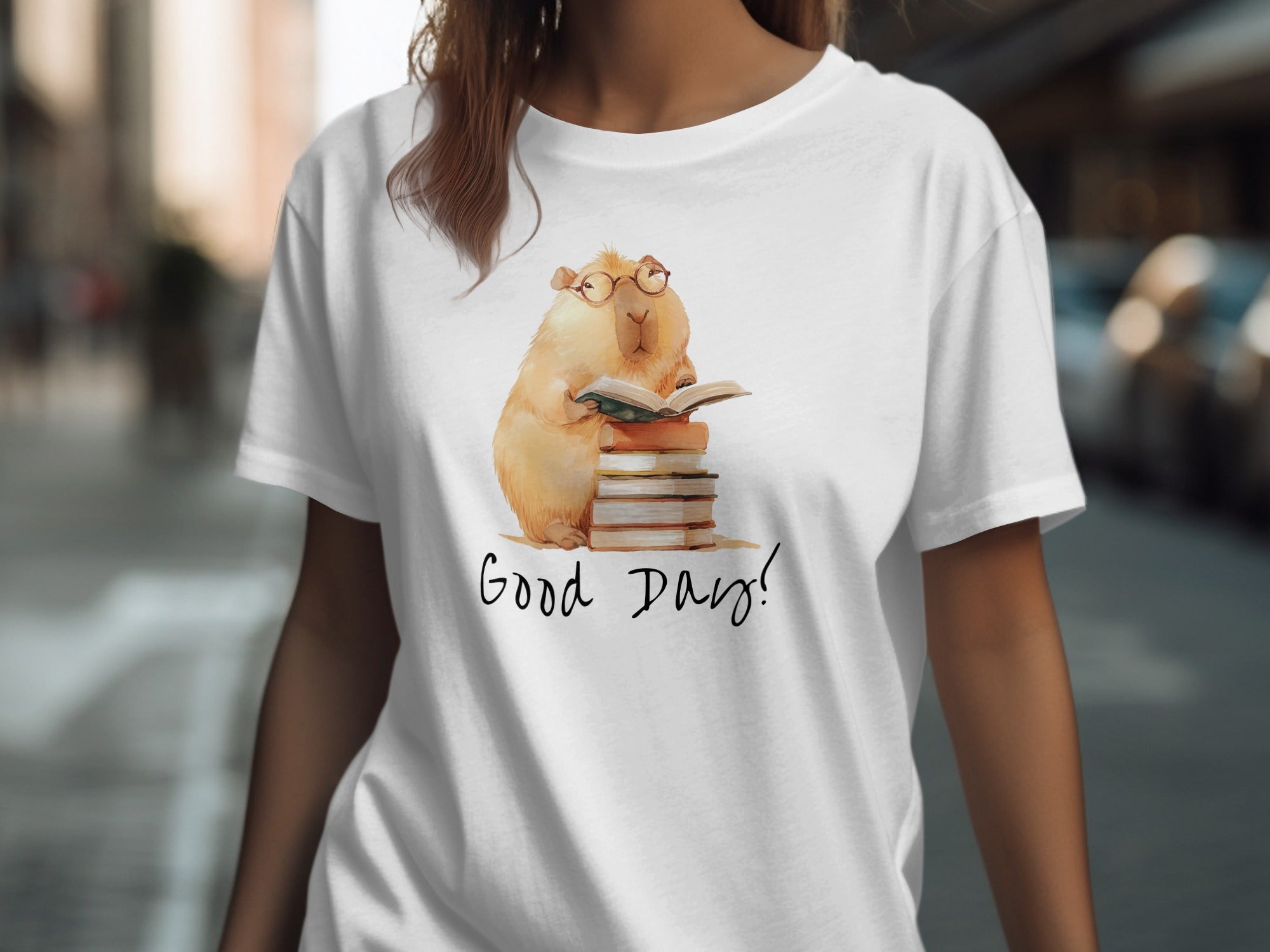 White t-shirt with illustration of a capybara reading a book on a stack of books.