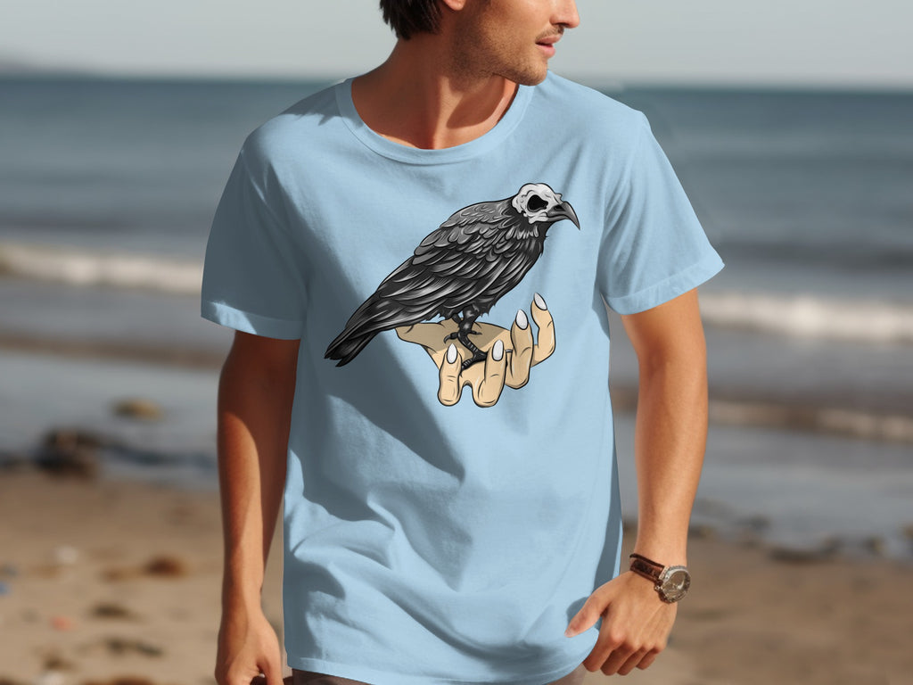 Light blue t-shirt with a black bird with a skull head perched on a hand graphic.
