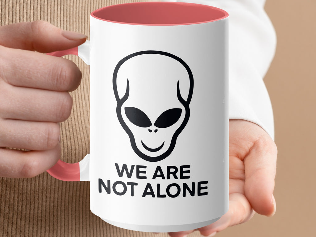 White mug with alien graphic and "WE ARE NOT ALONE" text.