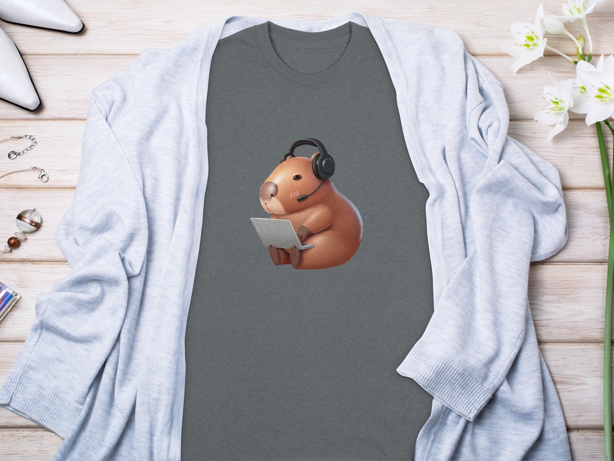 Capybara wearing headphones, using a laptop, printed on a dark grey t-shirt.
