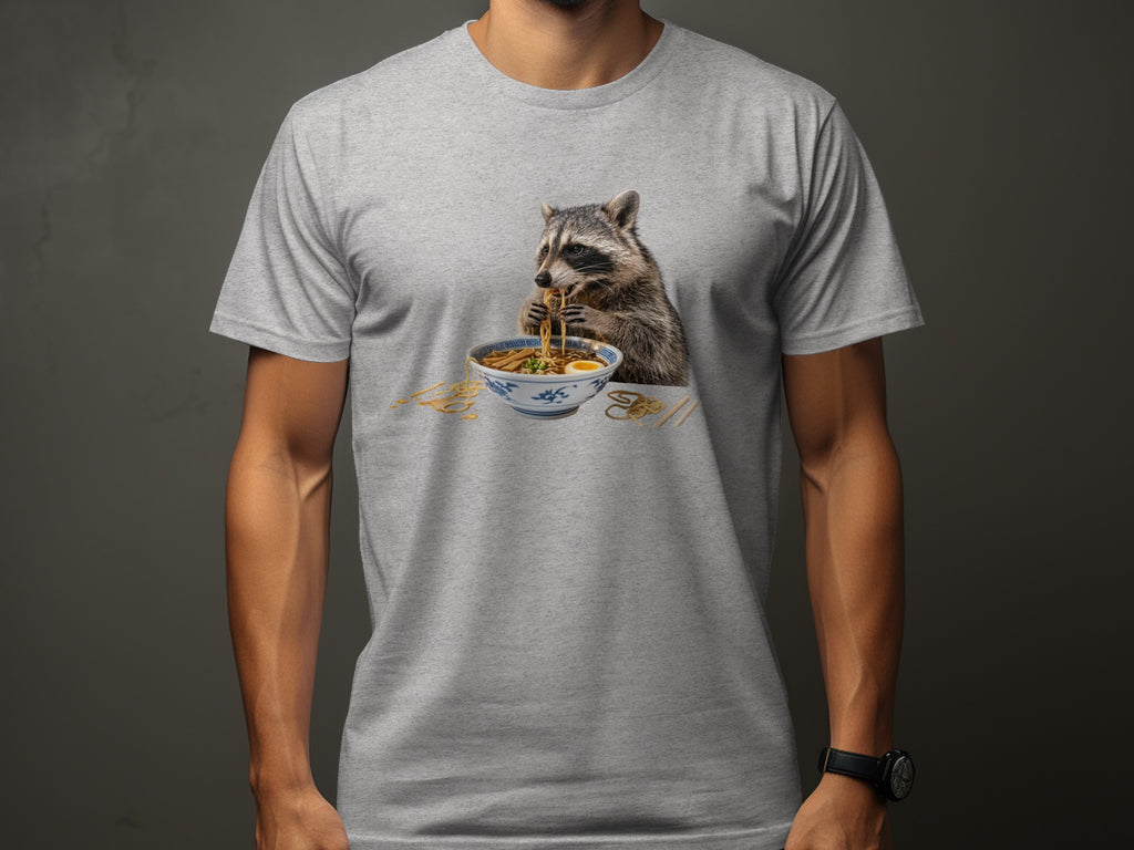 Raccoon eating ramen noodles from a bowl on a gray t-shirt.