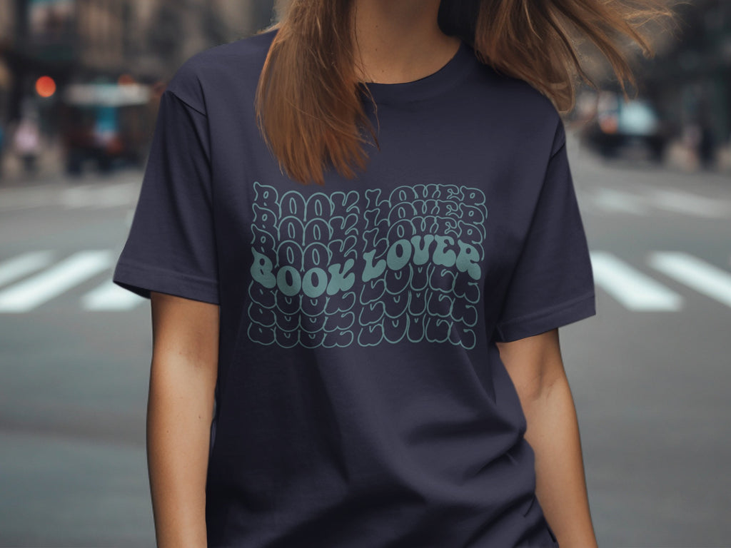 Dark navy t-shirt with repeated "BOOK LOVER" text in a wavy retro font.