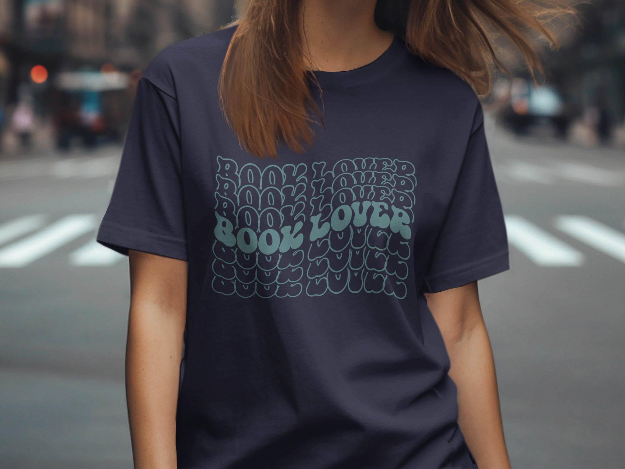 Dark navy t-shirt with repeated "BOOK LOVER" text in a wavy retro font.
