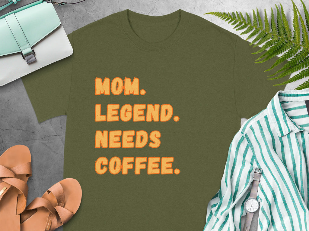 Olive green t-shirt with orange text reading "MOM. LEGEND. NEEDS COFFEE."
