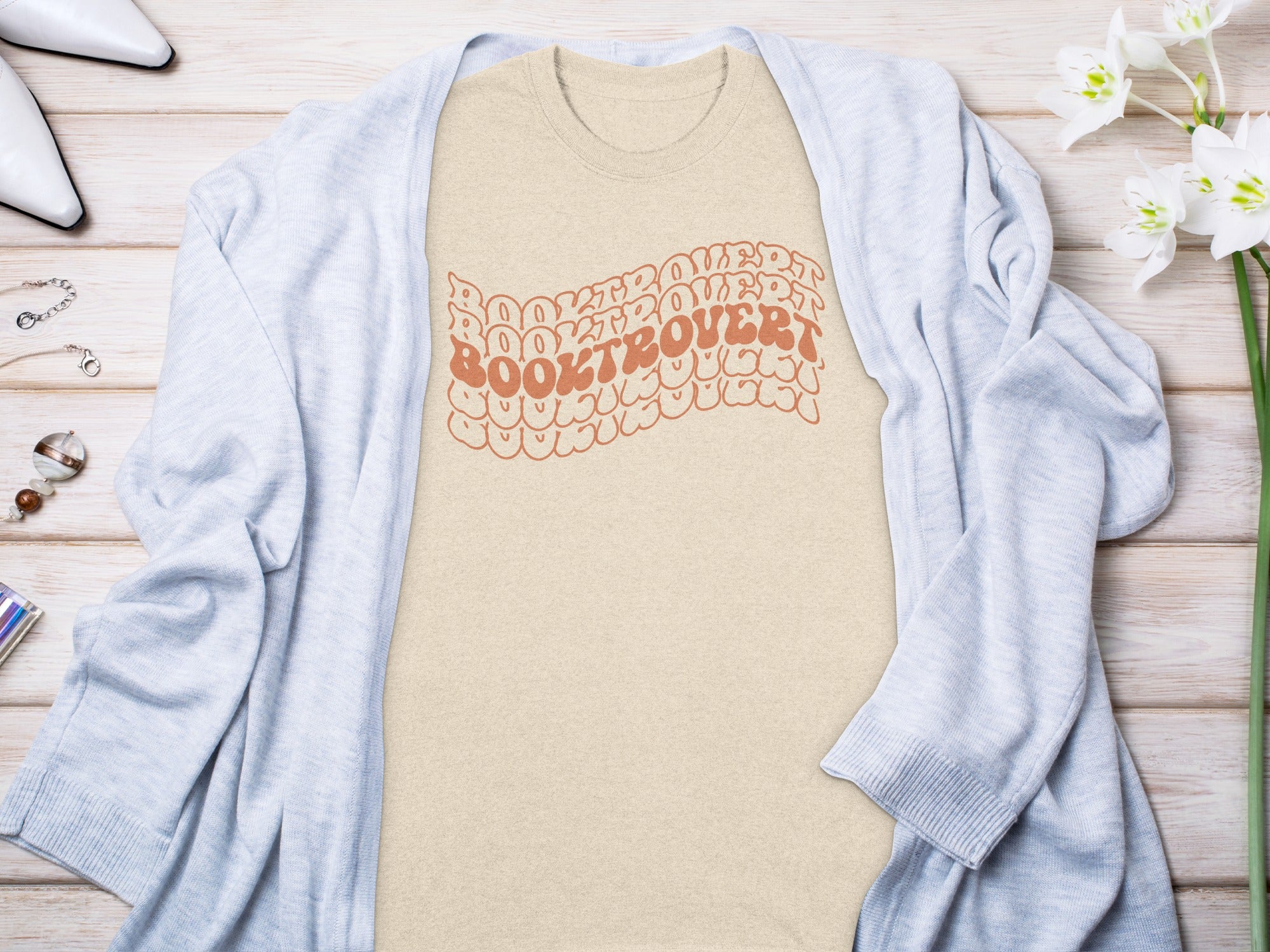 Light beige t-shirt with "BOOKTROVERT" text in curved, outlined orange letters.