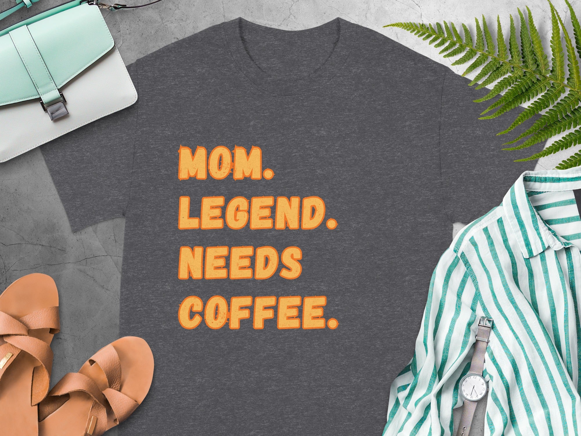 Dark gray t-shirt with orange text that reads "MOM. LEGEND. NEEDS COFFEE."