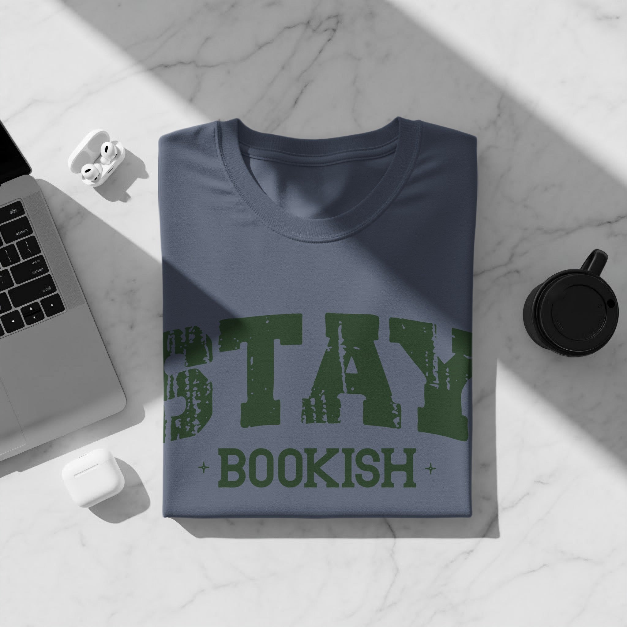 Blue t-shirt with green text "STAY BOOKISH" and a laptop.
