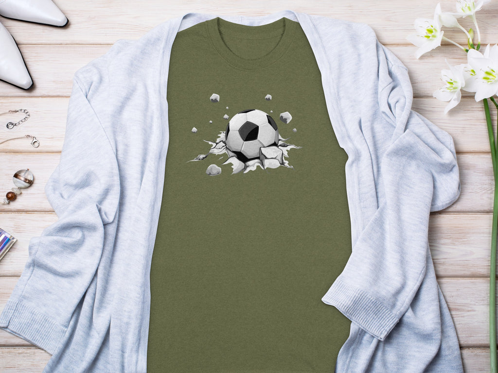 Green t-shirt with a graphic of a soccer ball breaking through the fabric.