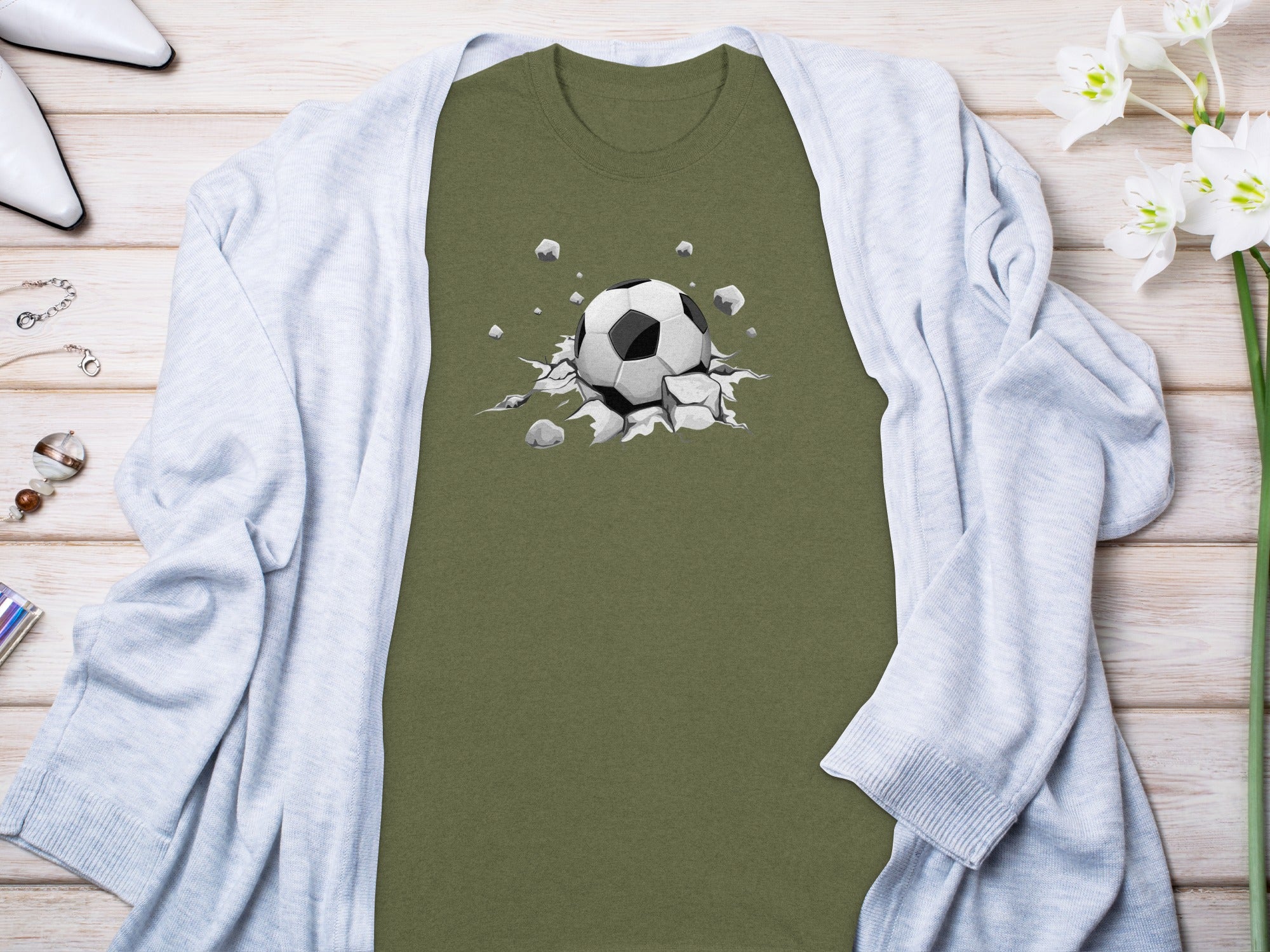Green t-shirt with a graphic of a soccer ball breaking through the fabric.