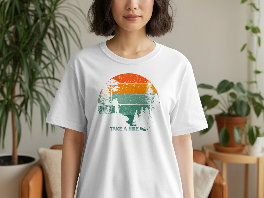 White t-shirt with a circular vintage-style graphic of a hiker and trees, with "TAKE A HIKE" text.