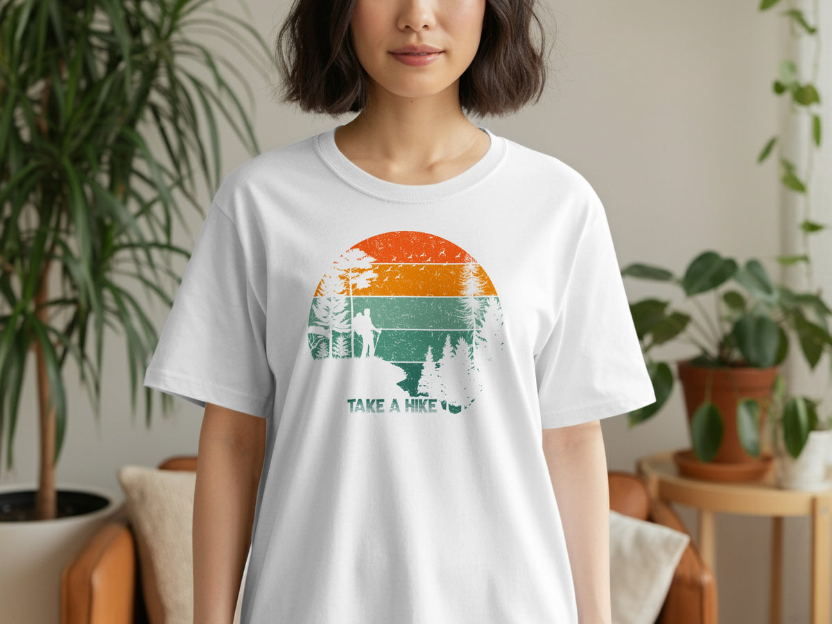 White t-shirt with a circular vintage-style graphic of a hiker and trees, with "TAKE A HIKE" text.