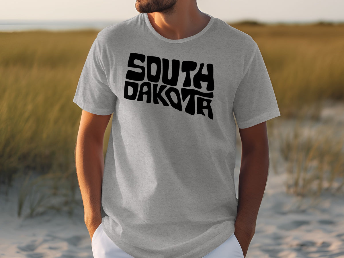 Grey t-shirt with black "SOUTH DAKOTA" text, worn by a person outdoors.
