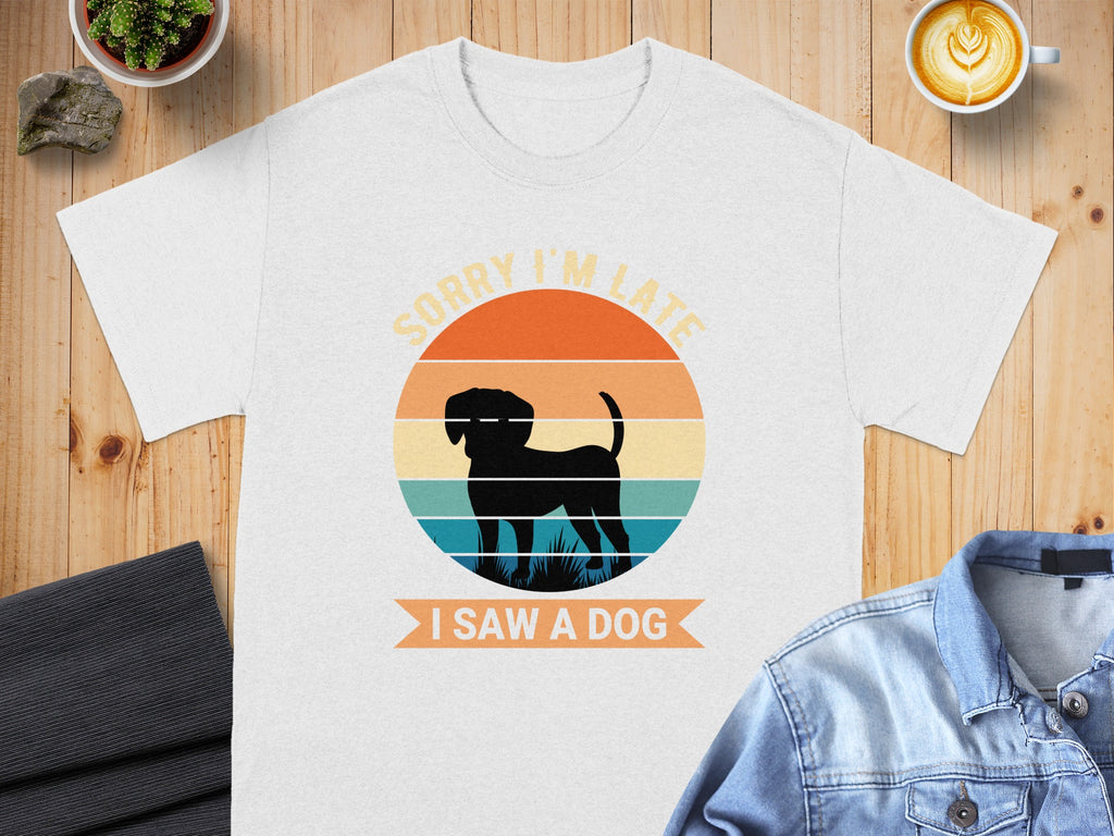 White t-shirt with a retro sunset graphic of a dog and text "SORRY I'M LATE I SAW A DOG."