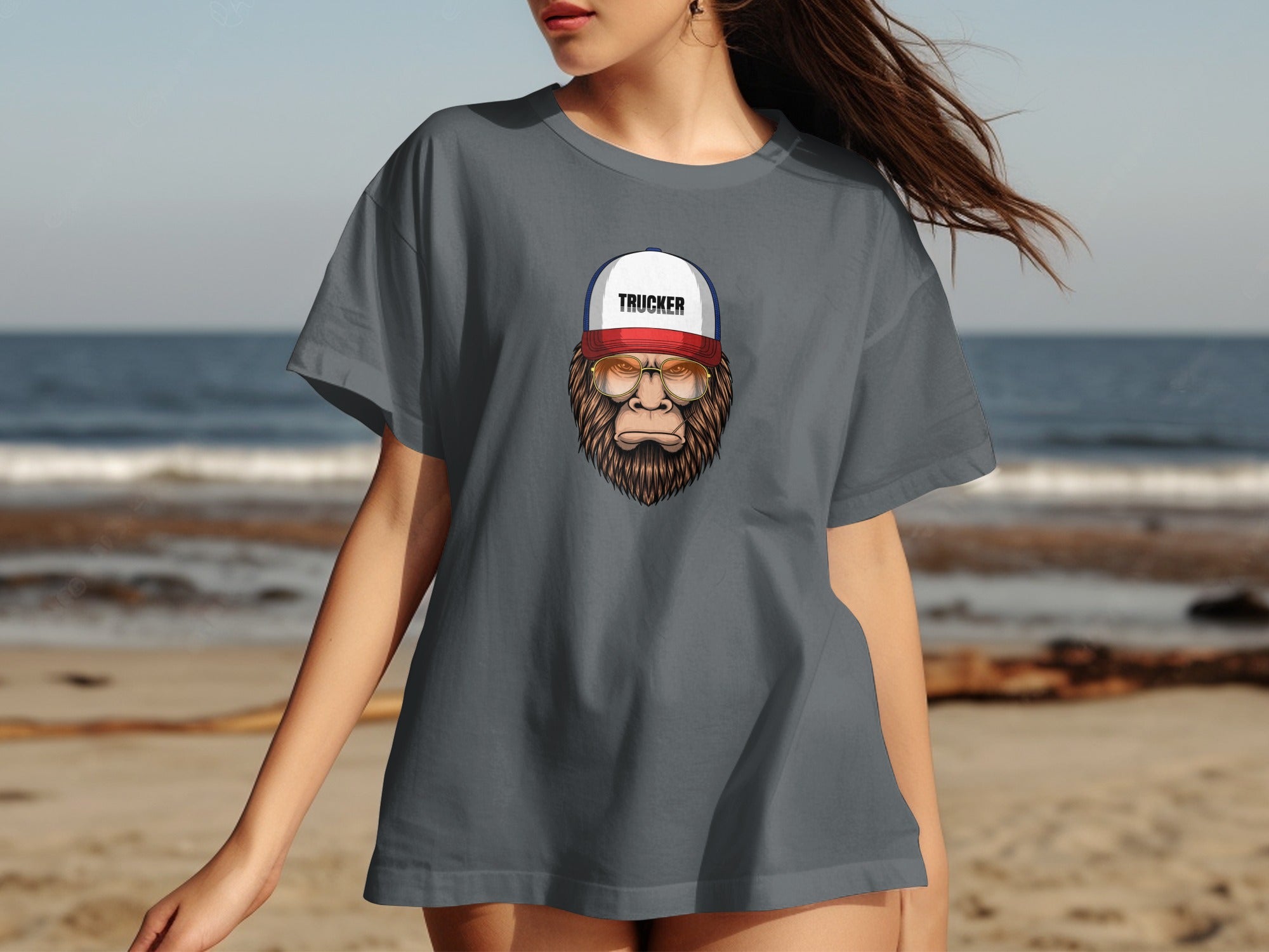 Gray t-shirt featuring a Bigfoot wearing glasses and a trucker hat with the word "TRUCKER".