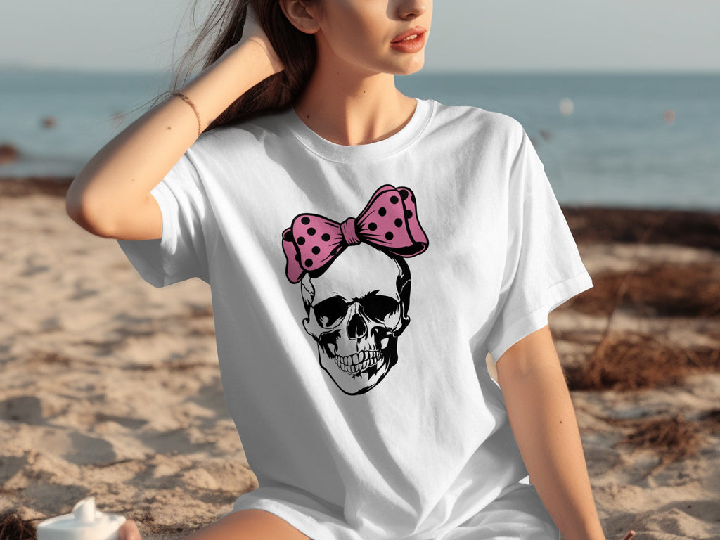 White t-shirt with black skull graphic wearing pink polka dot bow.