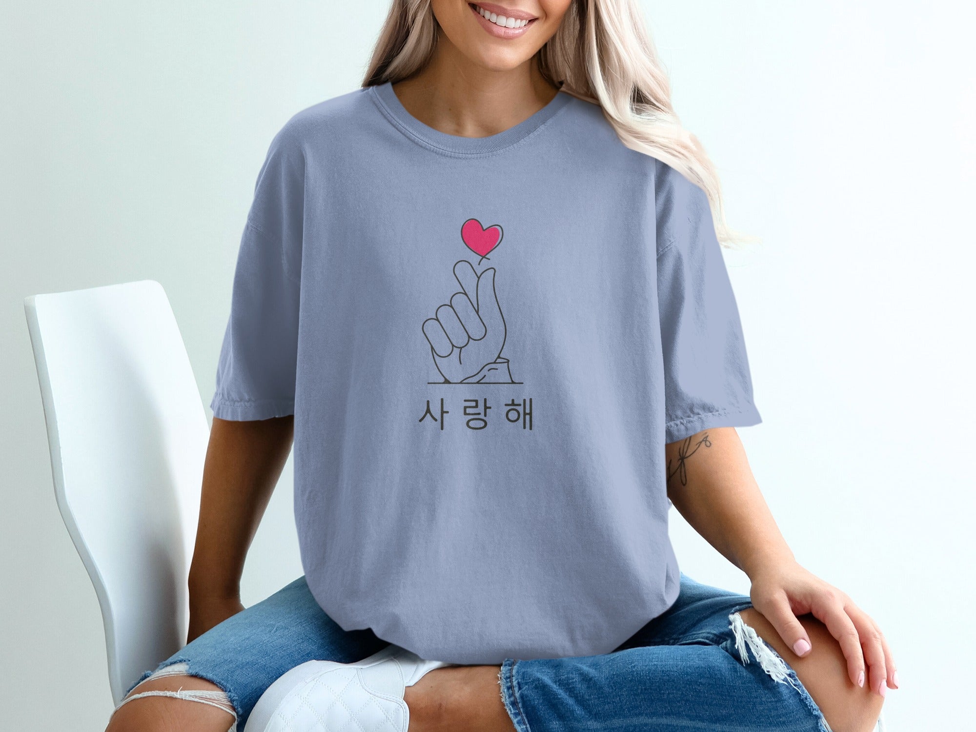 Light blue t-shirt with Korean text and finger heart gesture graphic.