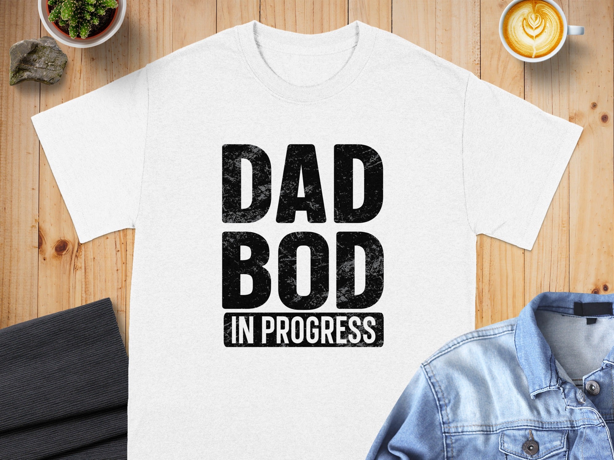 White t-shirt with black distressed text: DAD BOD IN PROGRESS.