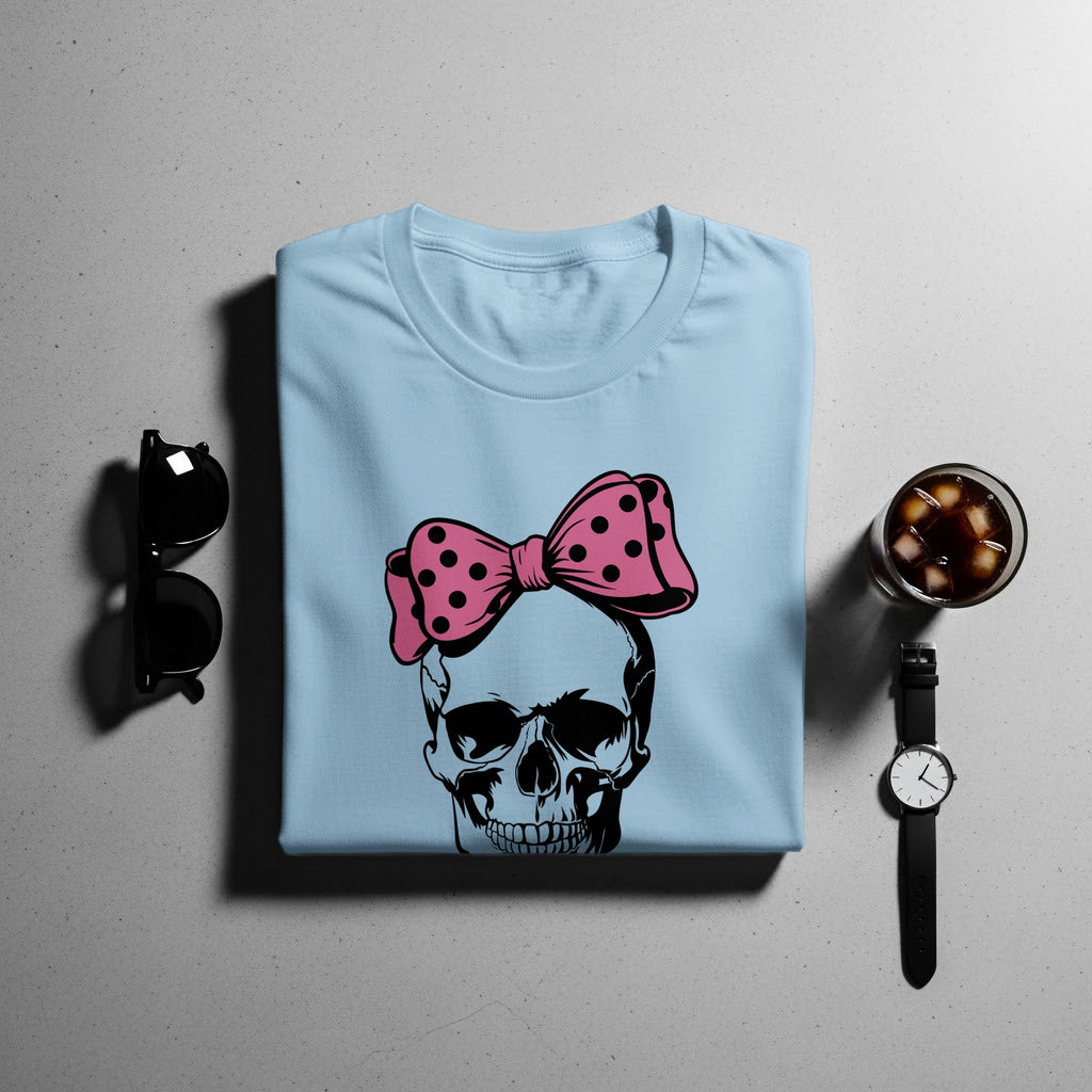 Light blue t-shirt with a black skull graphic wearing a pink polka dot bow.