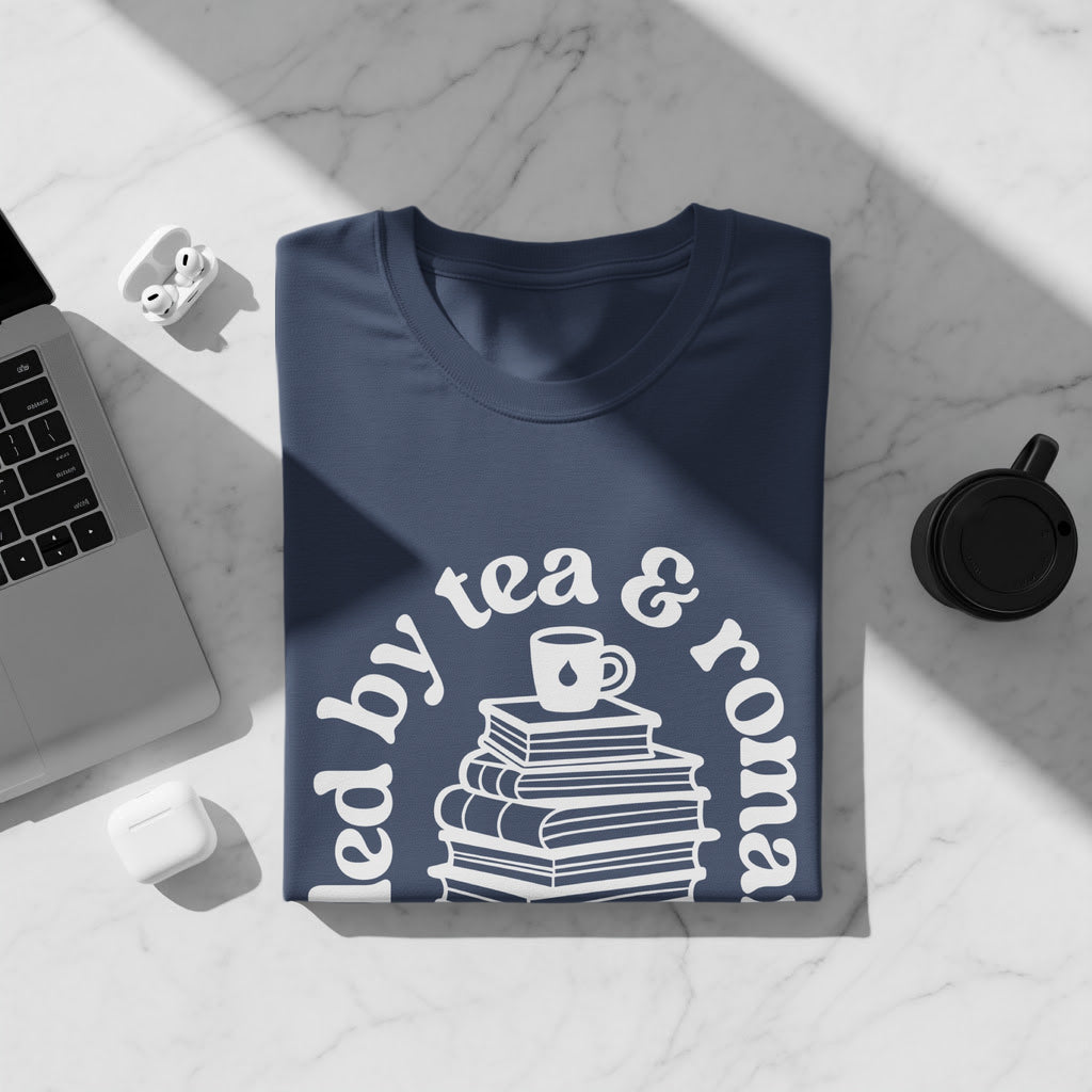 Navy t-shirt with "led by tea & roma" text and stack of books graphic.