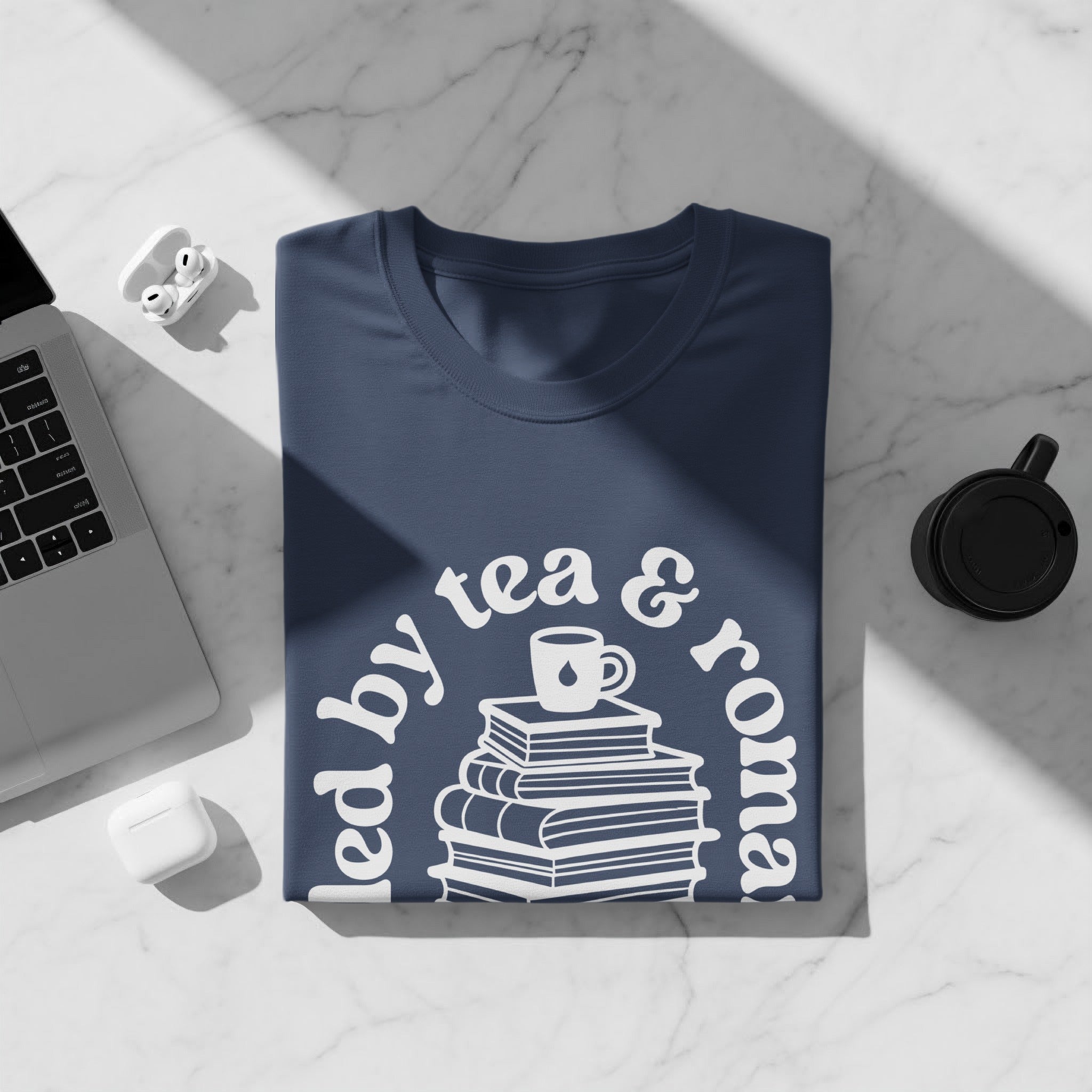 Navy t-shirt with "led by tea & roma" text and stack of books graphic.