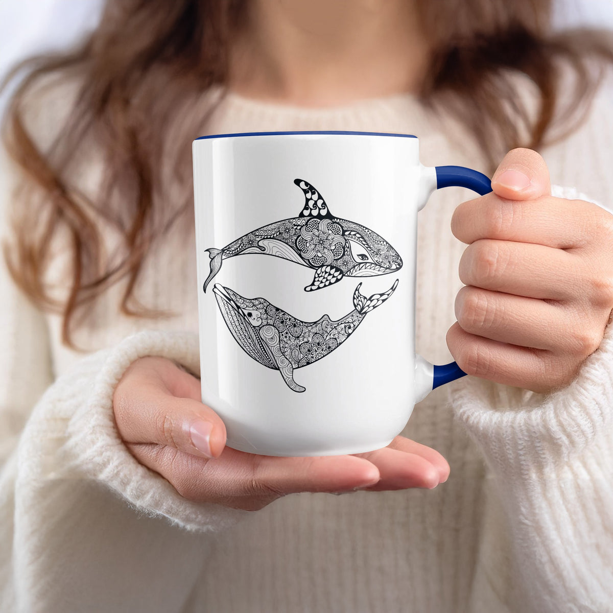 White mug with blue trim featuring a black mandala design of an orca and a whale.