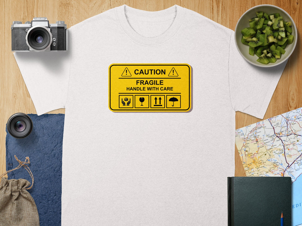 White t-shirt with yellow "CAUTION FRAGILE HANDLE WITH CARE" graphic.