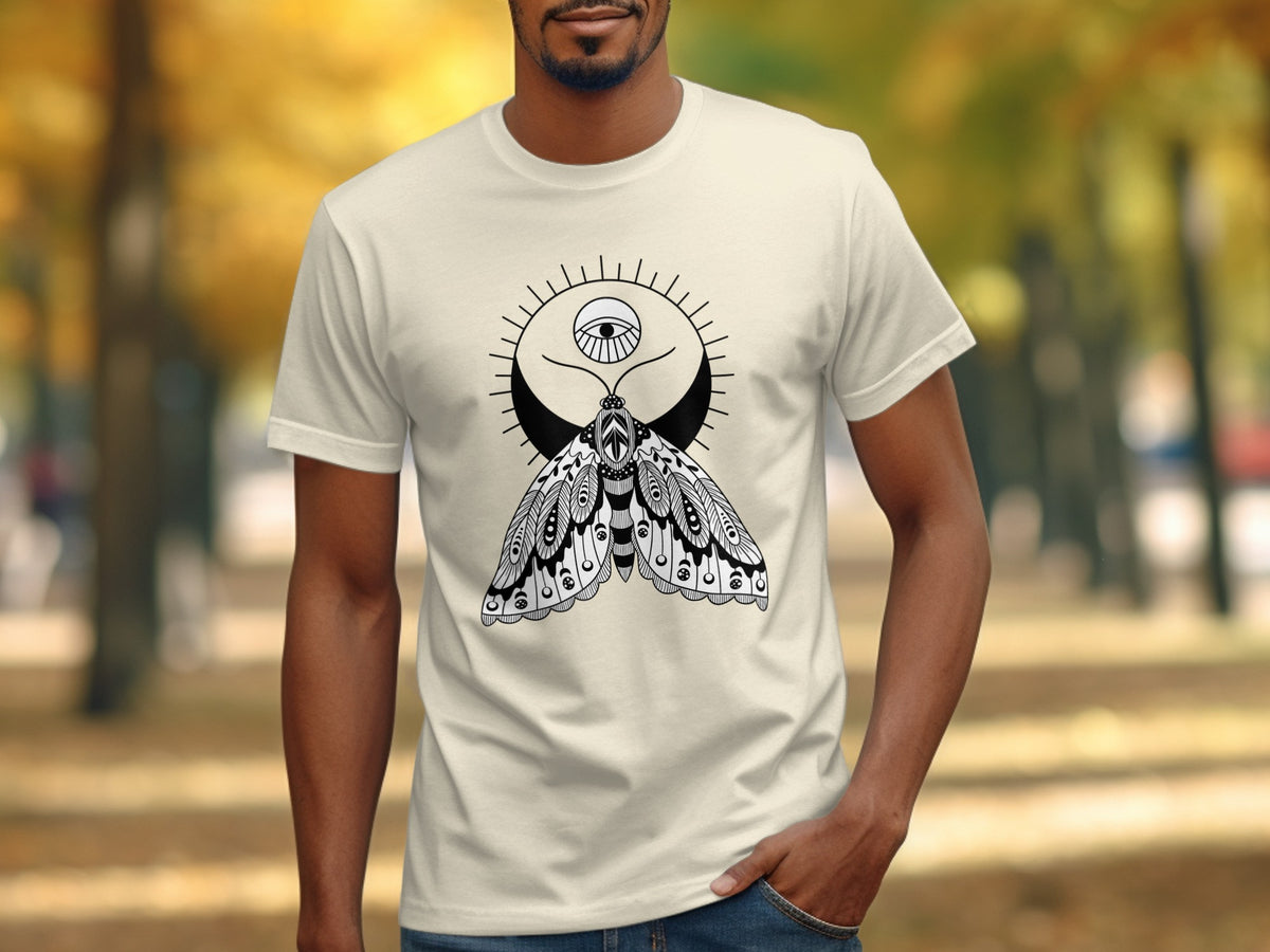 T-shirt with black and white moth, moon, and eye design on light cream shirt.