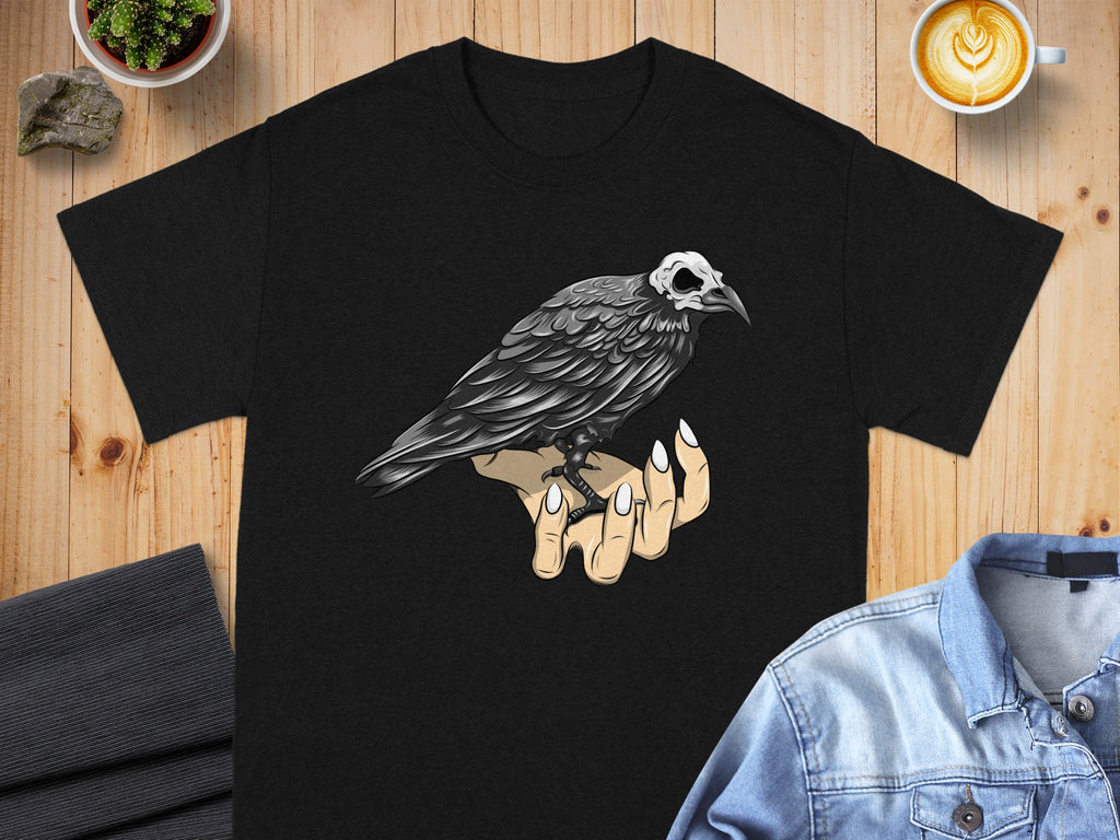 Black t-shirt with a graphic of a crow with a skull head on a hand.