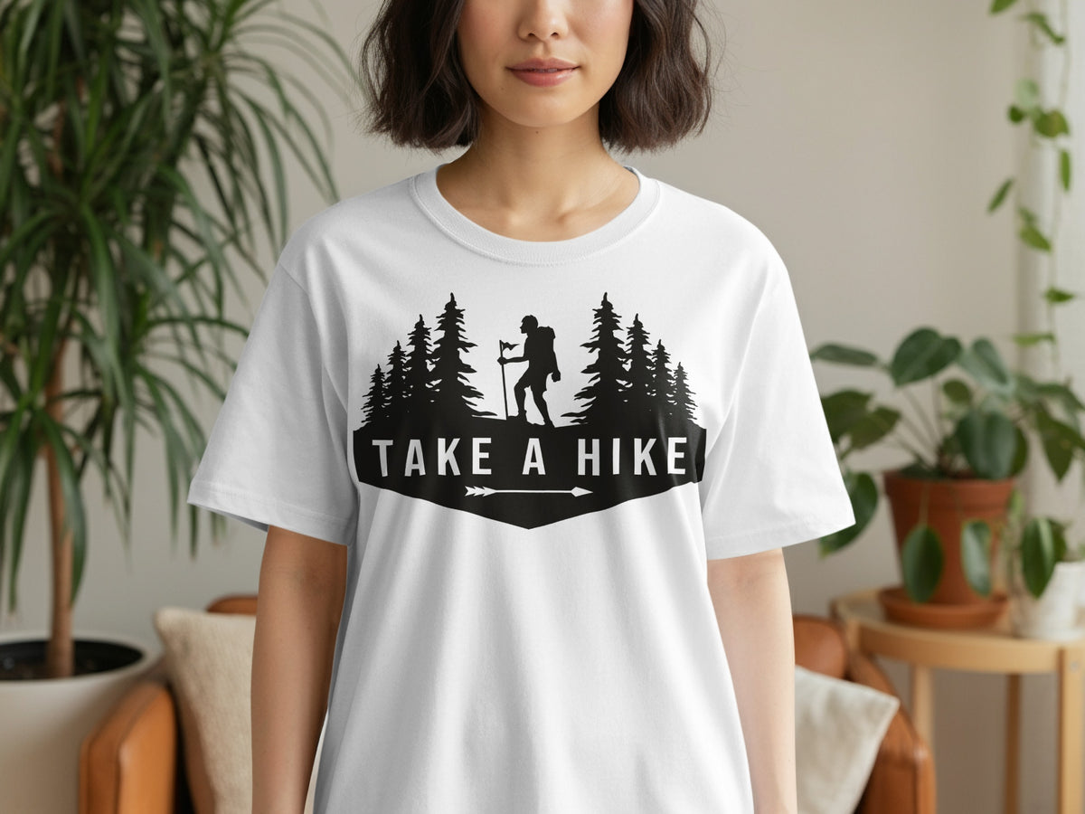 White t-shirt with black graphic featuring a hiker, trees, and the text "TAKE A HIKE".